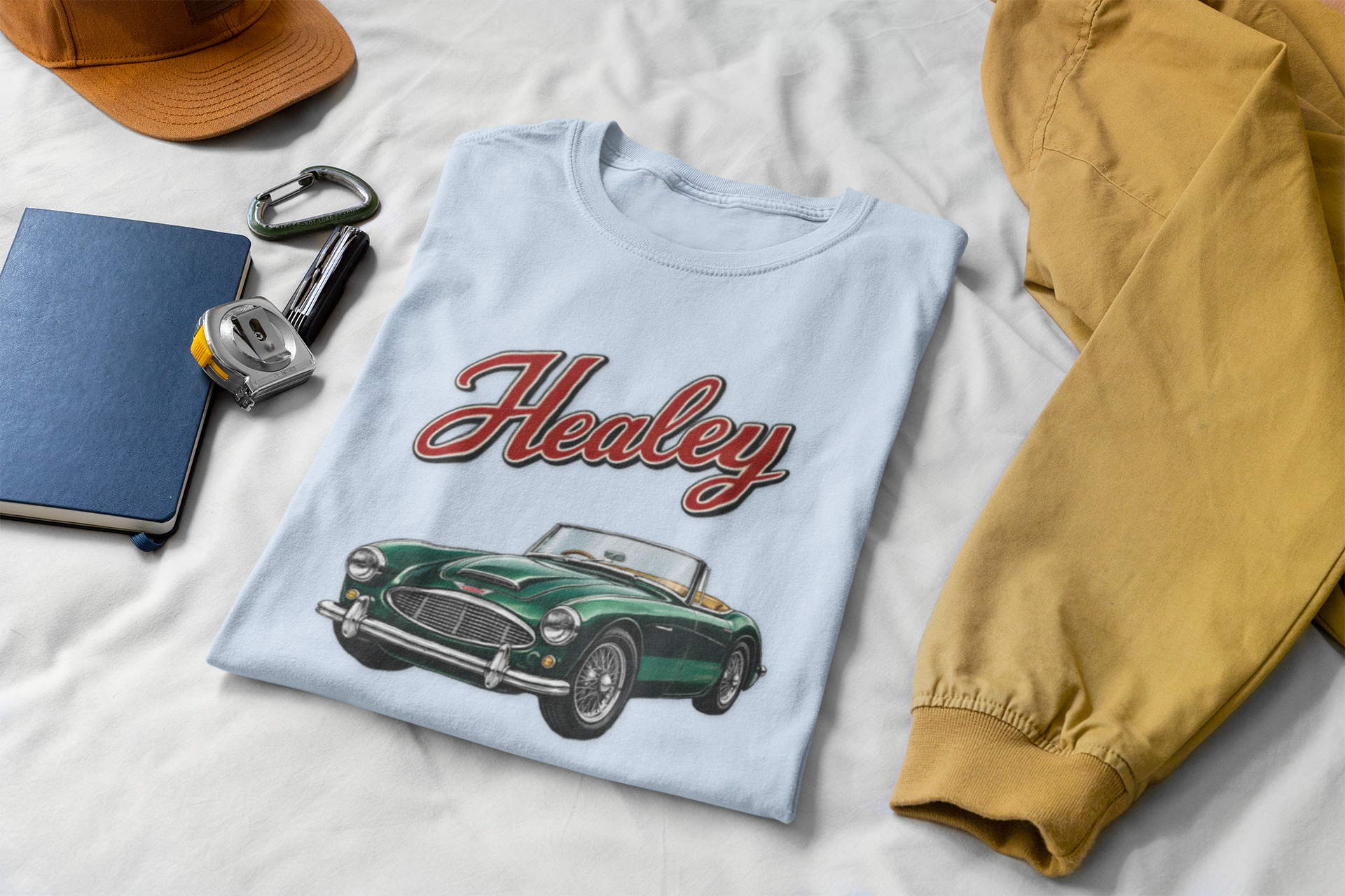 Light blue t-shirt with classic 'Healey' design on a white surface with accessories.