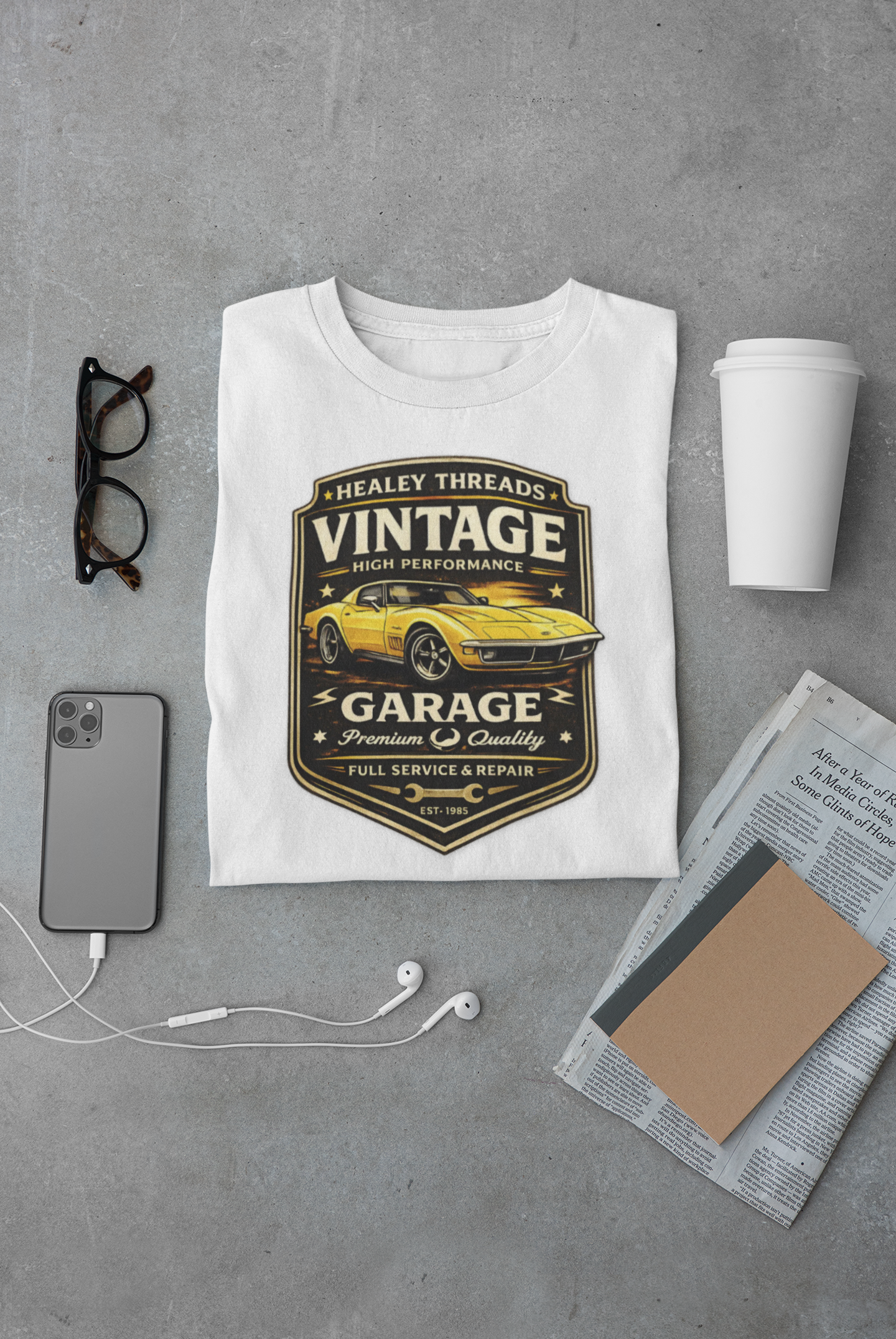 White t-shirt with vintage classic car graphic on a gray surface with accessories.