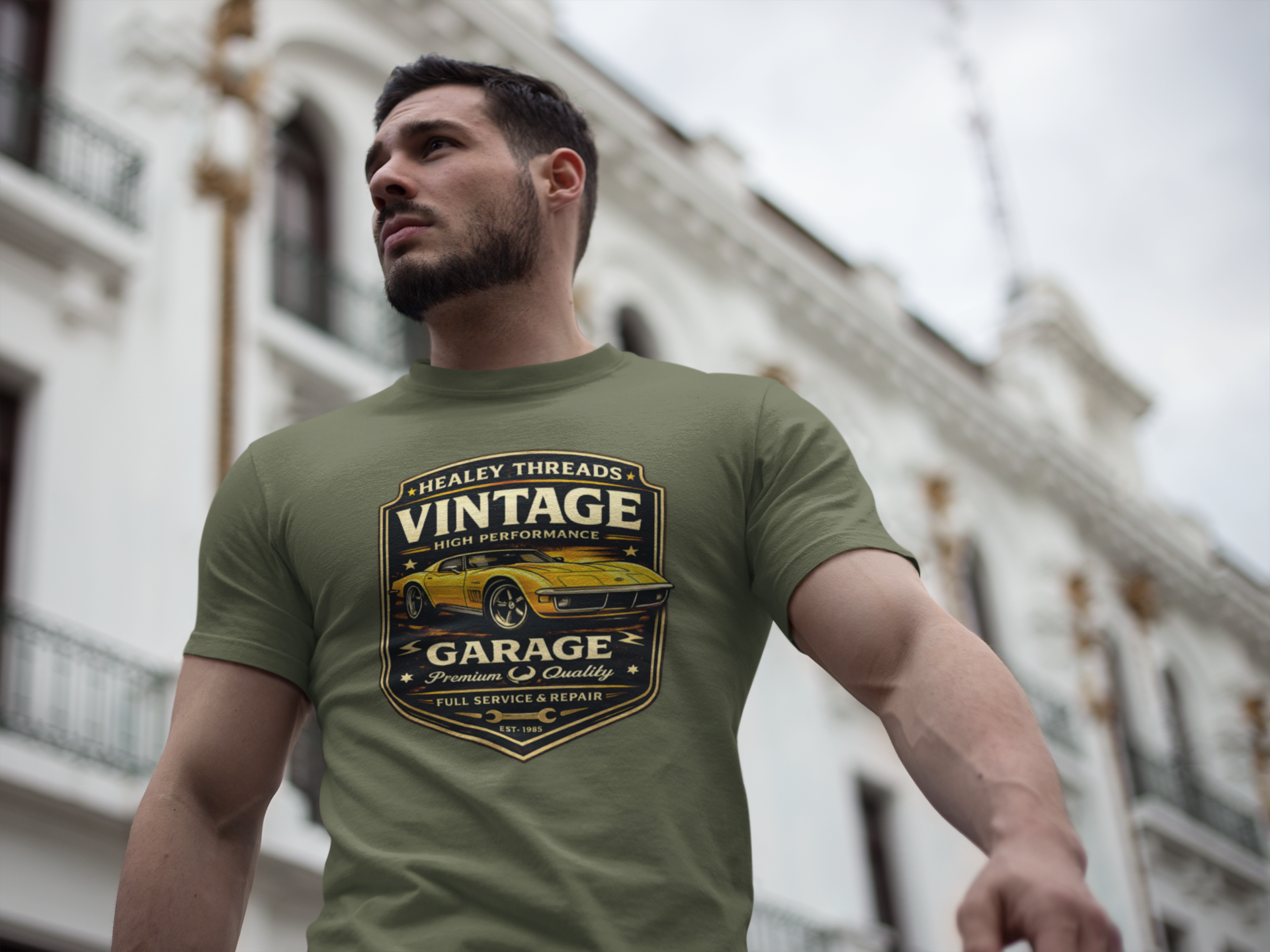 Man wearing a military green t-shirt with a vintage classic car  graphic design outdoors.