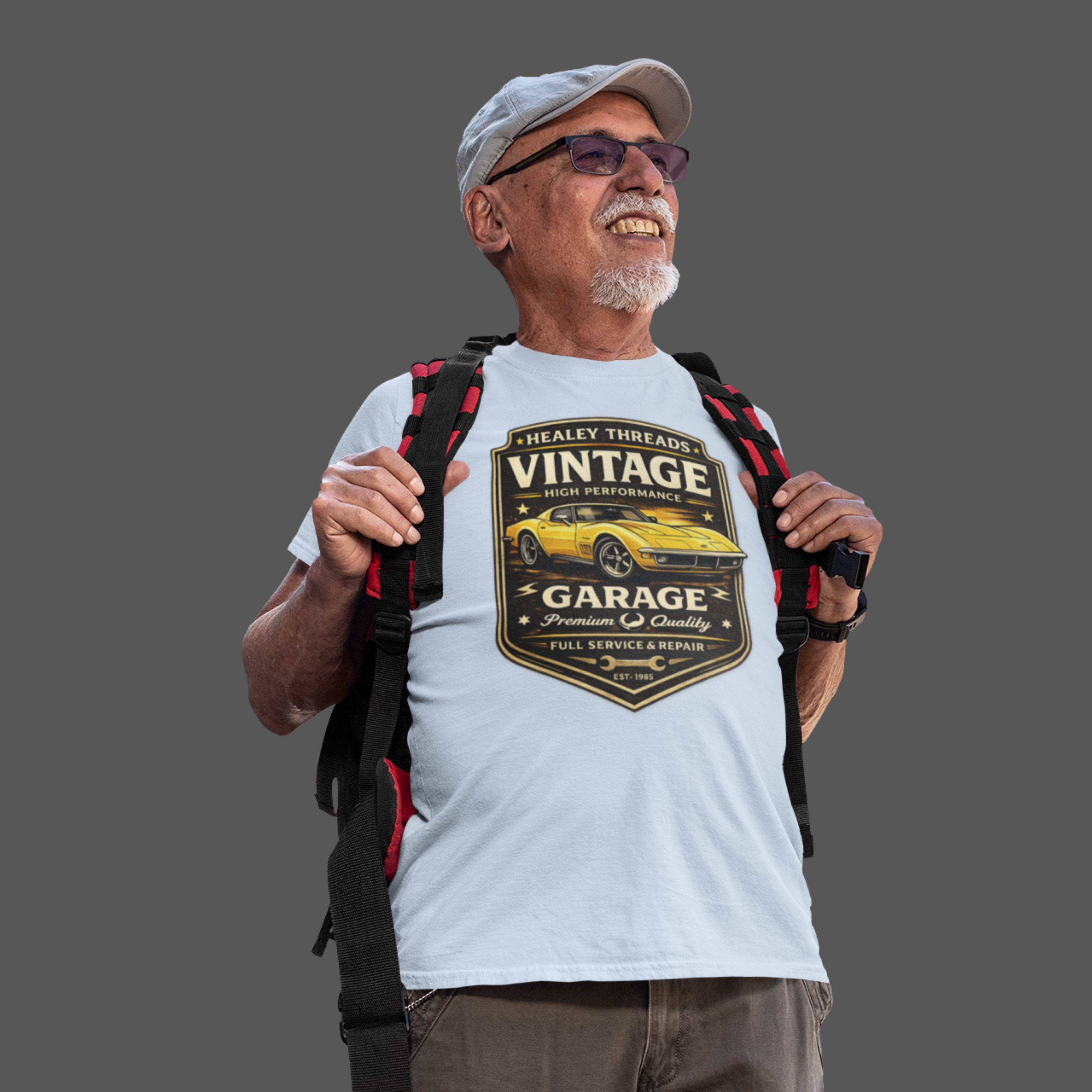 Man wearing a white t-shirt with a vintage classic car graphic and carrying a backpack on a gray background