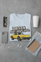 Light blue t-shirt with a yellow muscle car graphic and text 'Driven. Not Displayed.