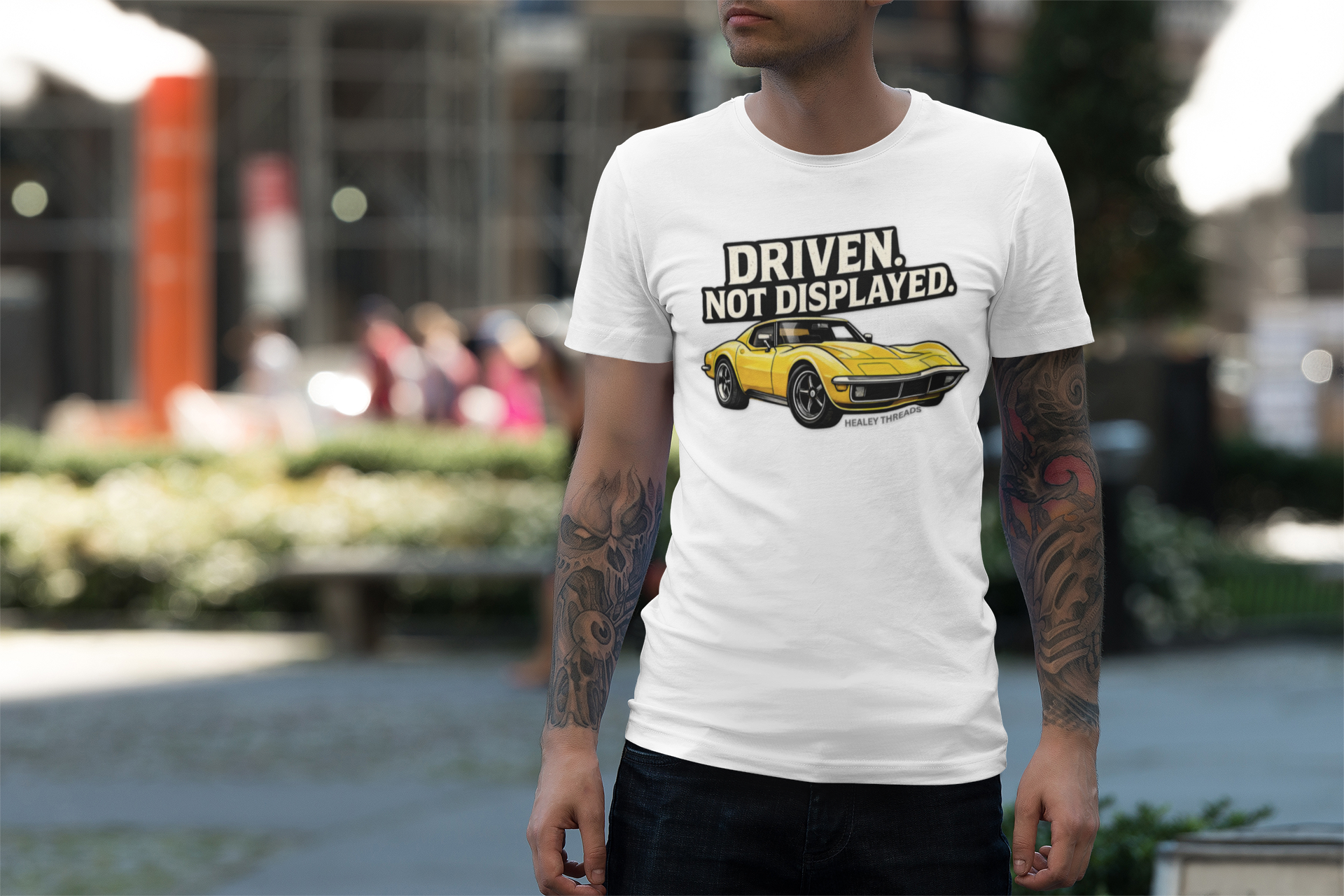 Man wearing a white t-shirt with a yellow muscle car graphic and text in an outdoor setting