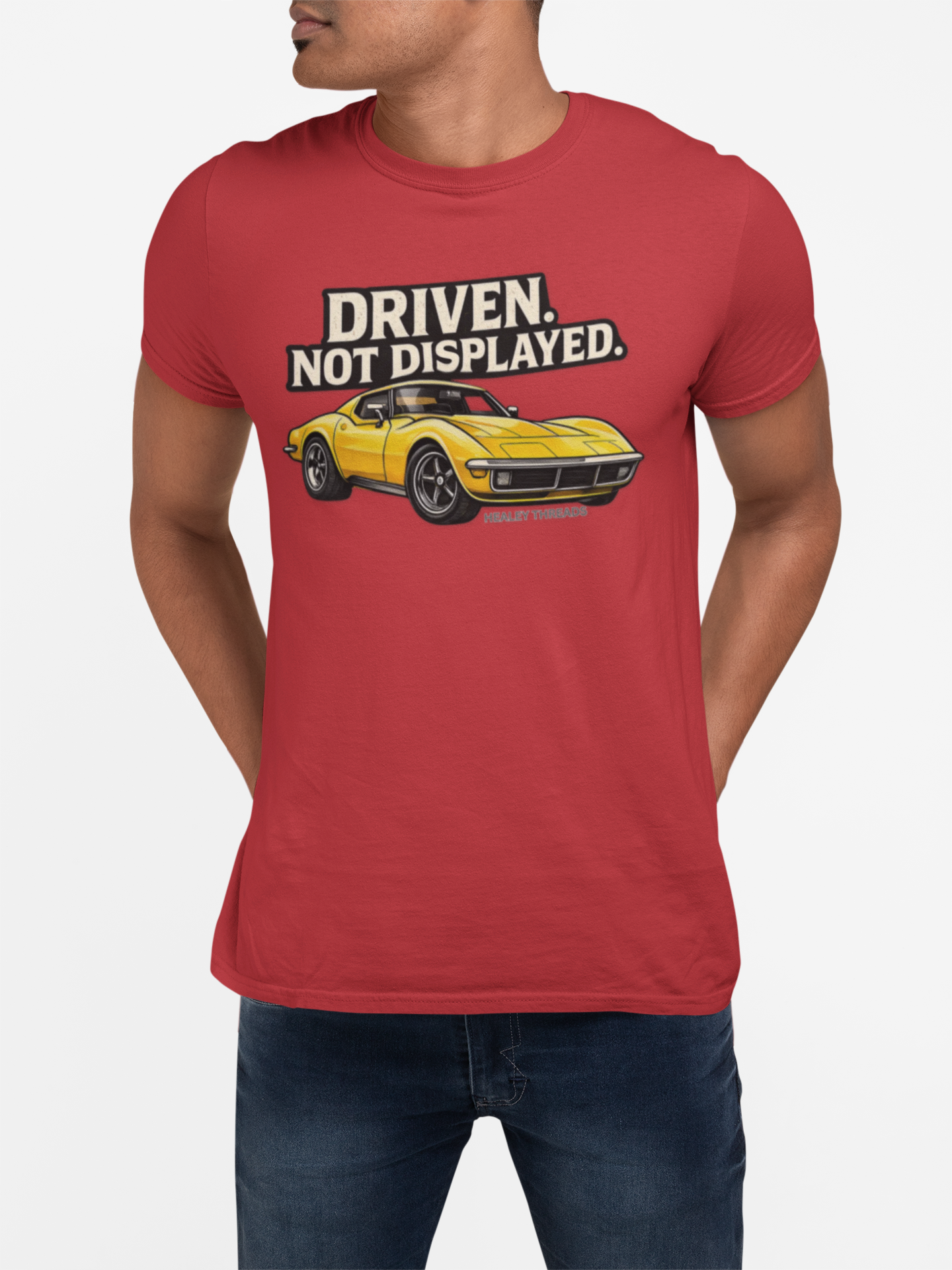 Red t-shirt with a yellow muscle car graphic and text 'Driven. Not Displayed.' worn by a person on a white background