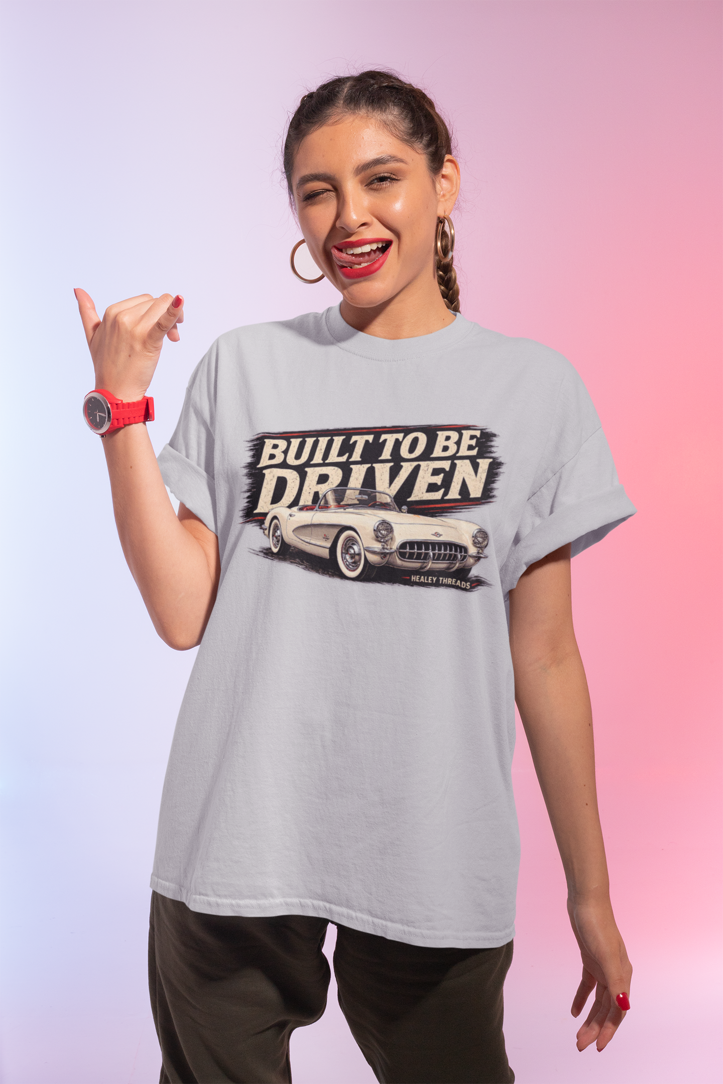 Woman wearing a light blue t-shirt with a built to be driven graphic and text, posing against a gradient background.