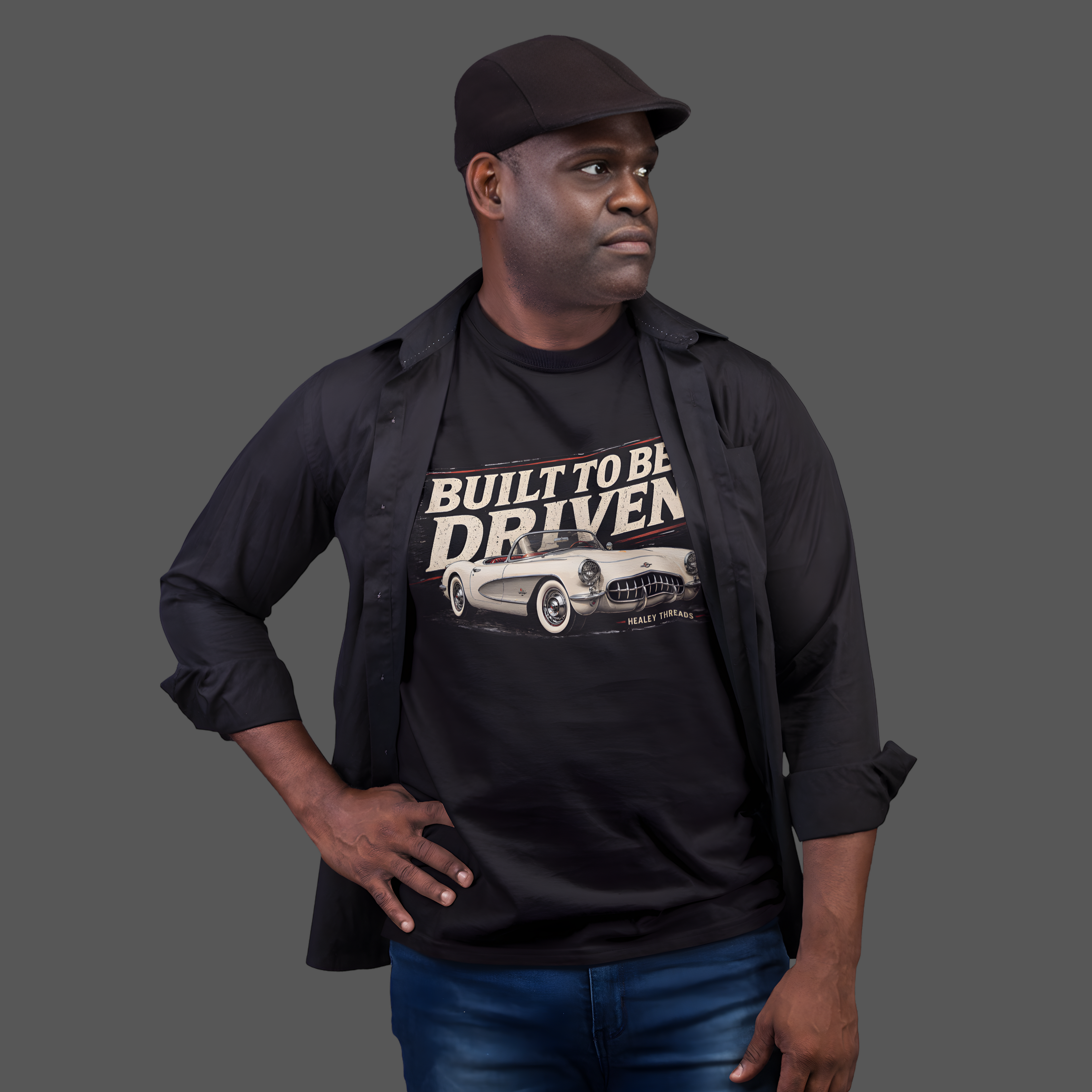 Man wearing a black shirt with 'Built to be Driven' graphic and text, standing against a gray background