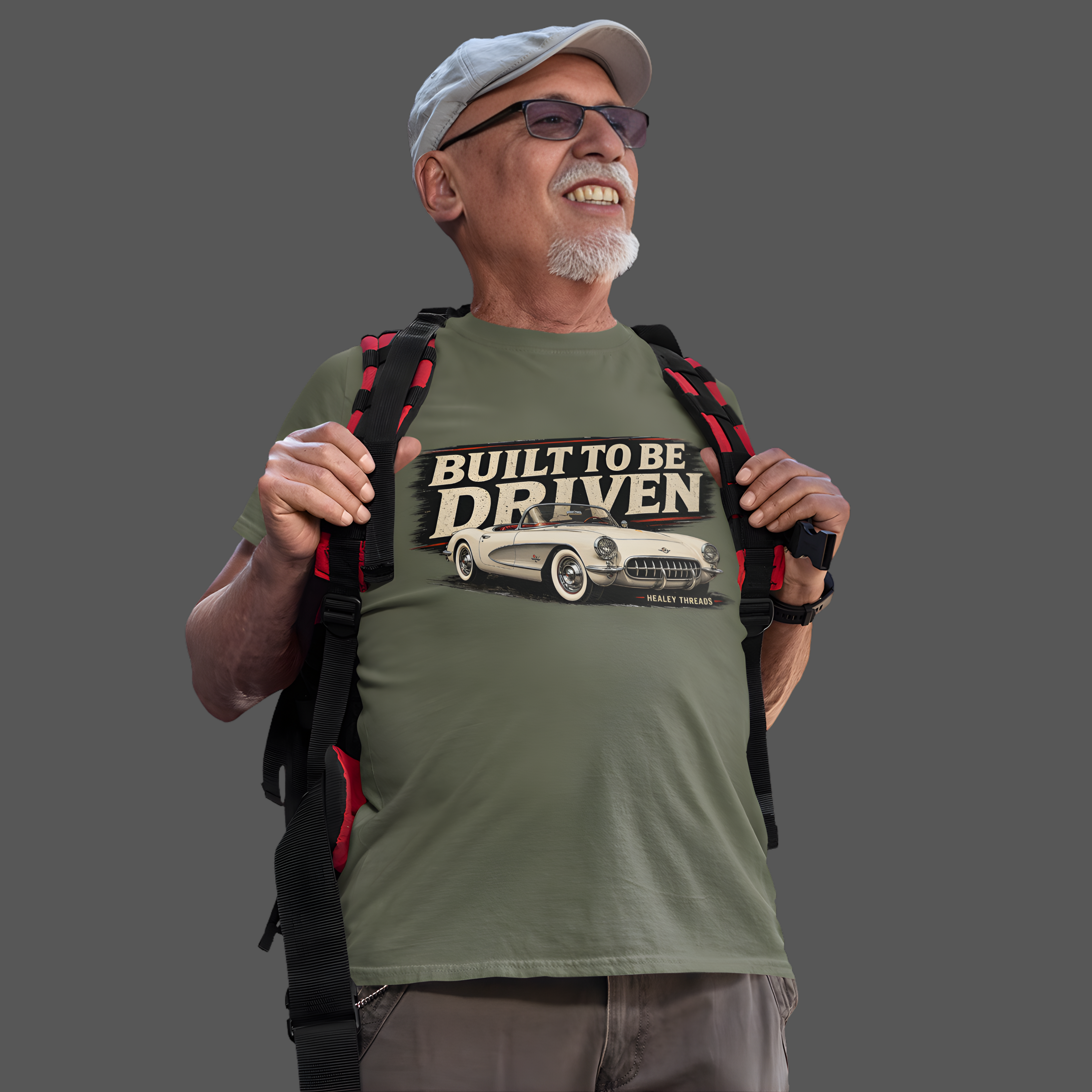 Man wearing a military green t-shirt with 'Built to be Driven' graphic and a backpack on a gray background