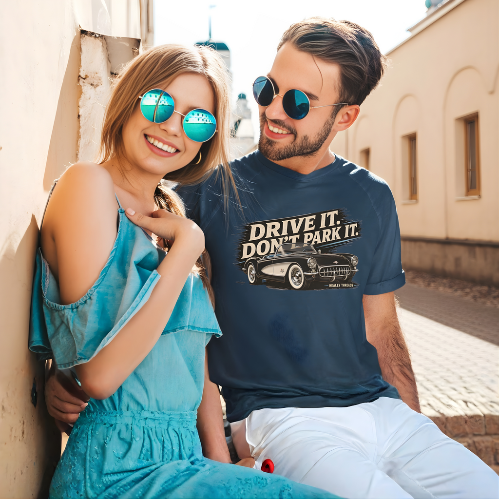 Man and woman sitting together with the man wearing a blue t-shirt with 'Drive It, Don't Park It' text and vintage car graphic.