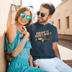 Man and woman sitting together with the man wearing a blue t-shirt with 'Drive It, Don't Park It' text and vintage car graphic.