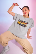 Woman wearing a gray t-shirt with a graphic built to be driven design on a gradient background