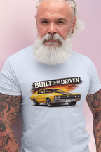Man wearing a white t-shirt with a graphic of a yellow car and text 'Built to be Driven' on a pink background