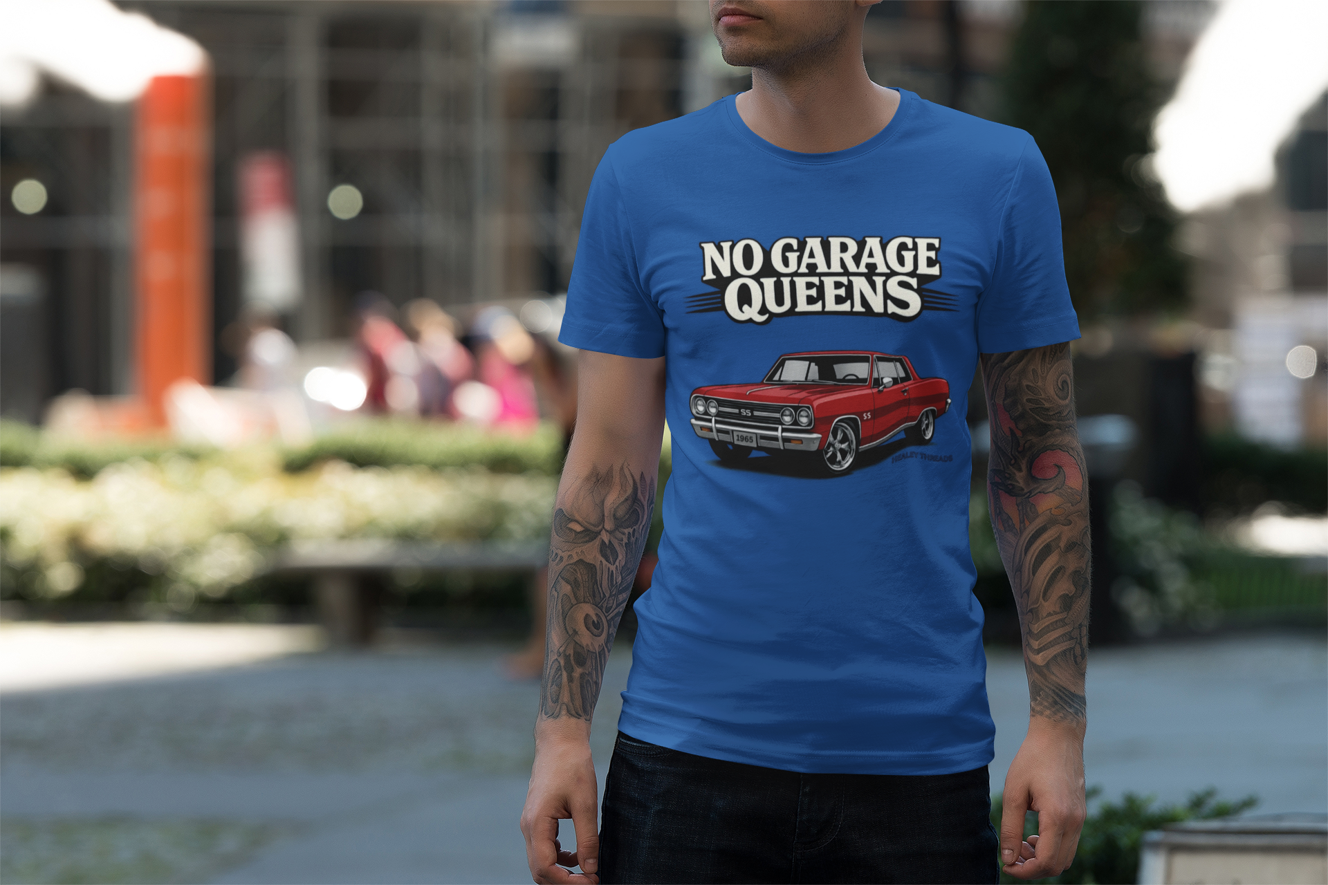 Man wearing a royal blue t-shirt with 'No Garage Queens' graphic in an outdoor setting