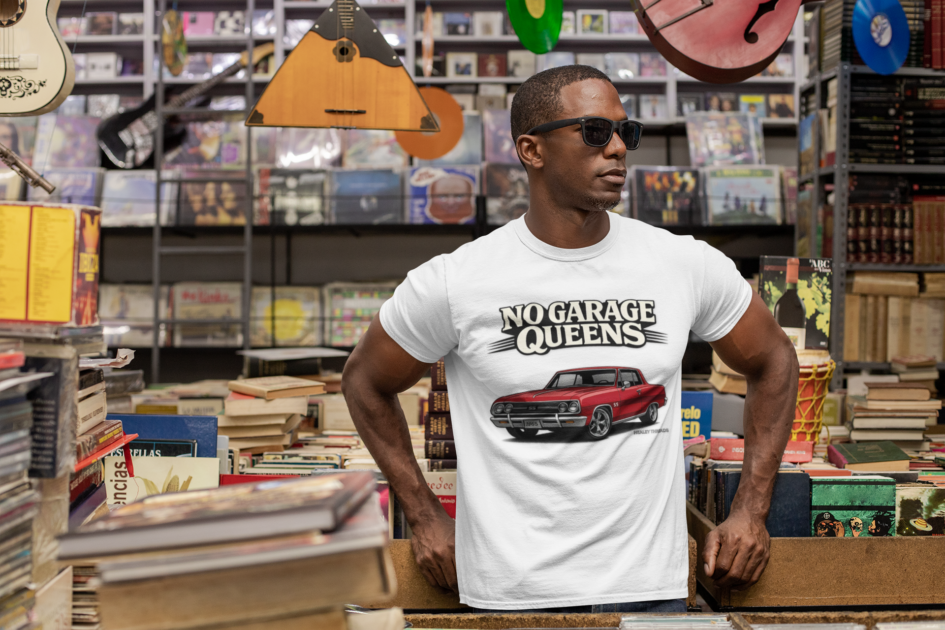 Man wearing a white t-shirt with 'No Garage Queens' graphic in a music store.