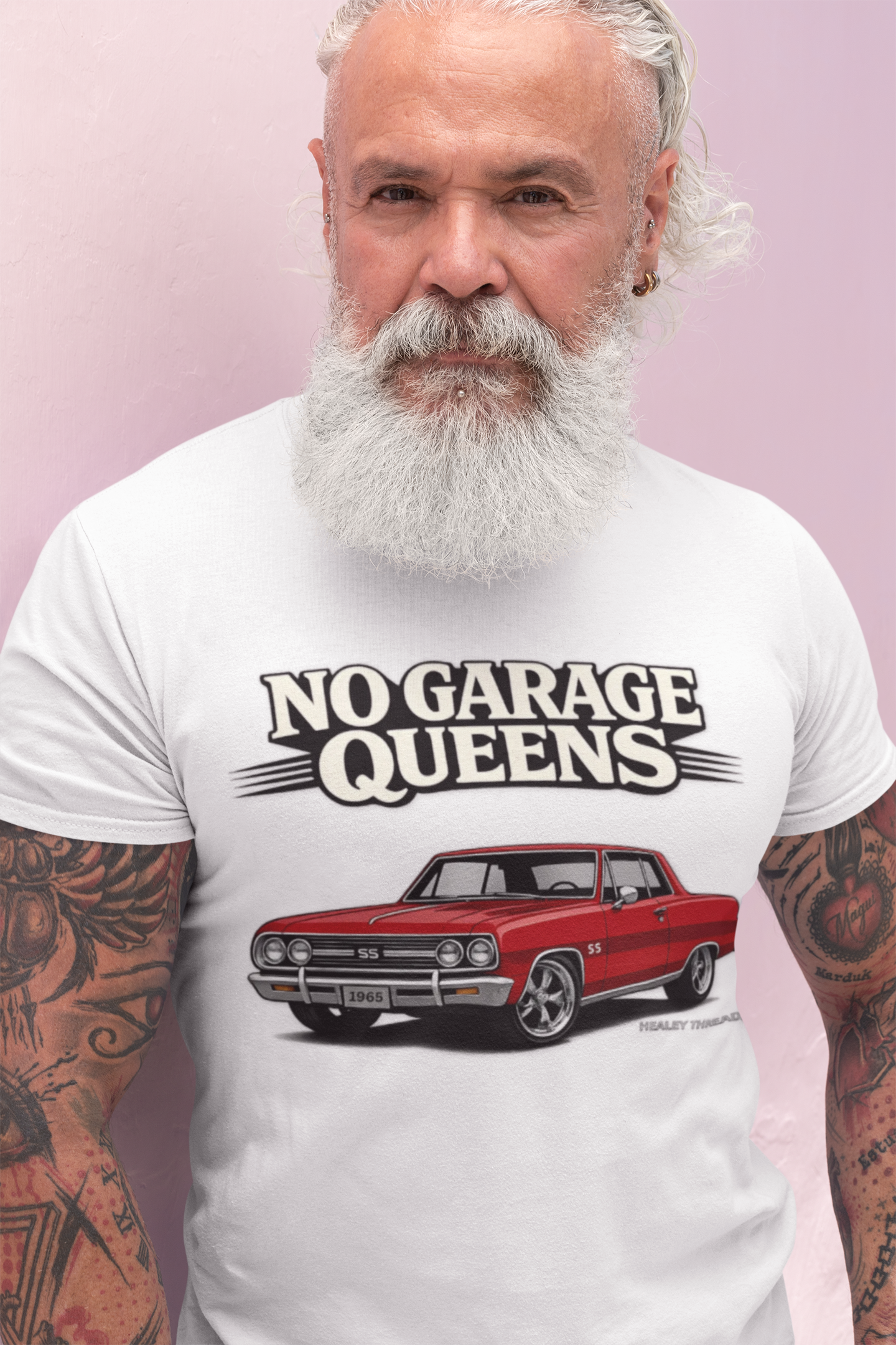 Man wearing a white t-shirt with a graphic of a red car and text 'No Garage Queens' on a pink background.
