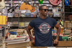 Man wearing a navy blue t-shirt with a graphic Healey Sprite design in a music store.