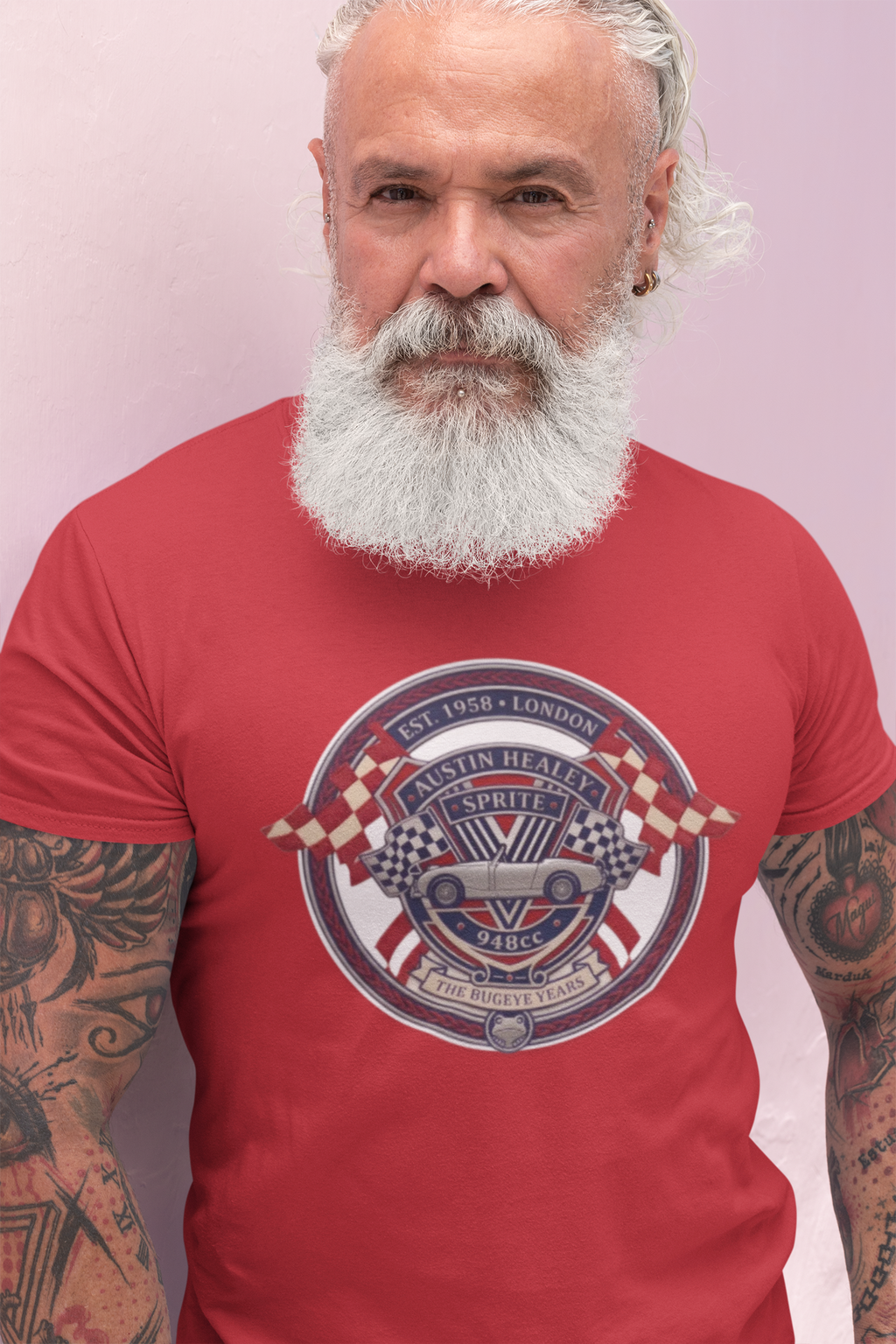 Man wearing a red t-shirt with a graphic Healey Sprite design on a light pink background