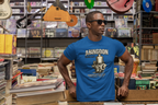 Man wearing a royal blue t-shirt with 'Abingdon' design in a store with books and musical instruments.