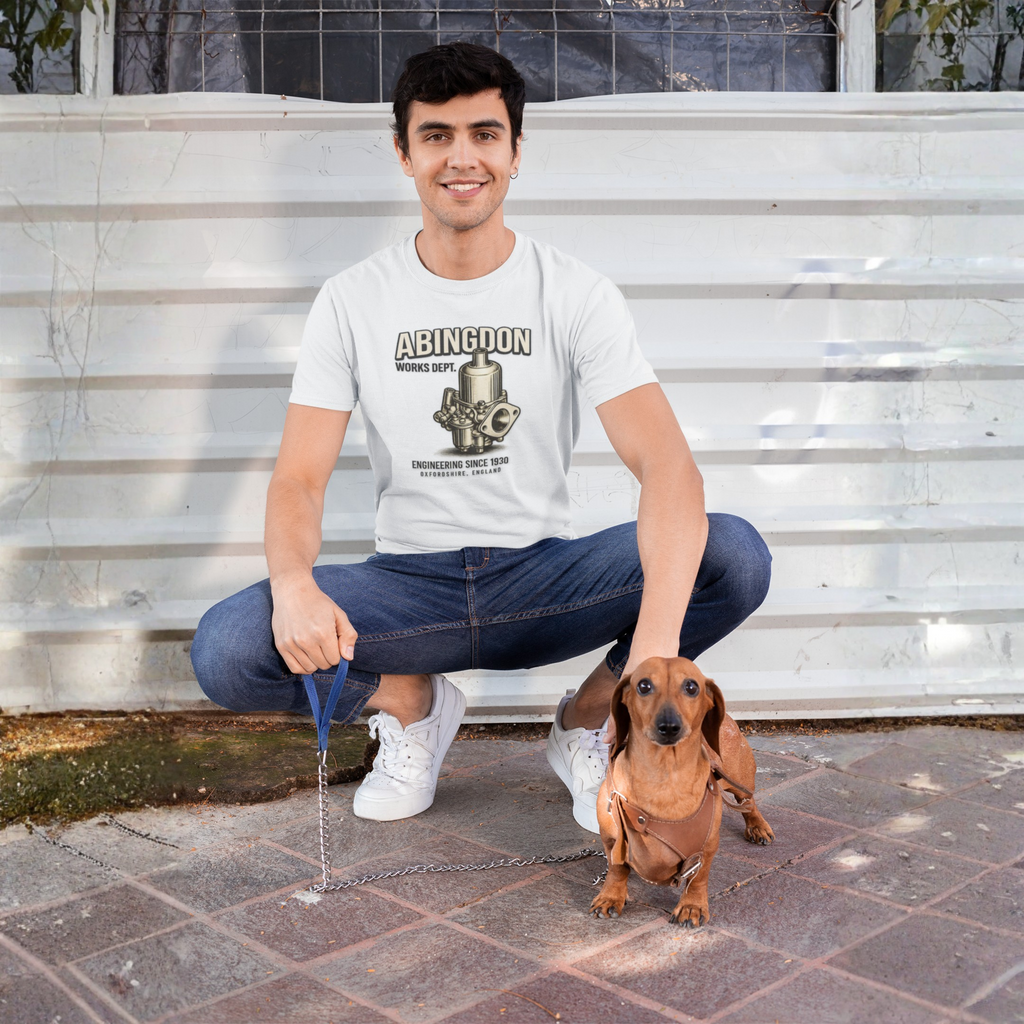 Man sitting on steps with a dog, wearing a white t-shirt with a 'Abingdon' graphic design.