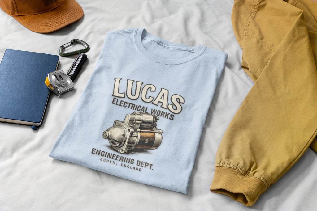 Light blue t-shirt with 'Lucas Electrical Works' design on a white surface with accessories.