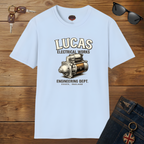 Light blue t-shirt with Lucas Electrical Works graphic on a wooden surface with sunglasses and keys.