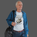 Man wearing a 'Lucas Electrical Works' light blue t-shirt with a blue jacket and carrying a black bag on a gray background