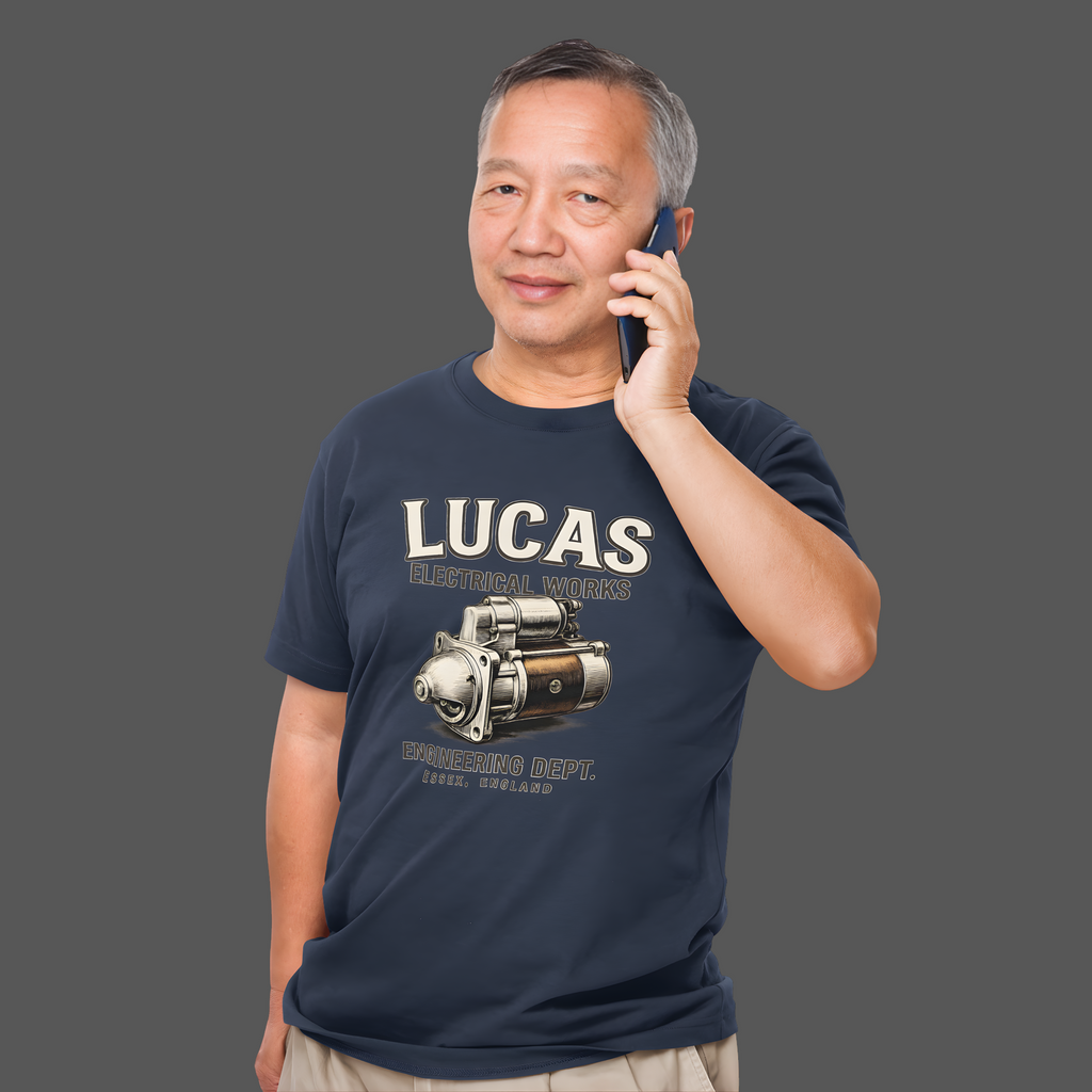 Man wearing a navy blue t-shirt with Lucas Electrical Works graphic and text, talking on a phone against a gray background
