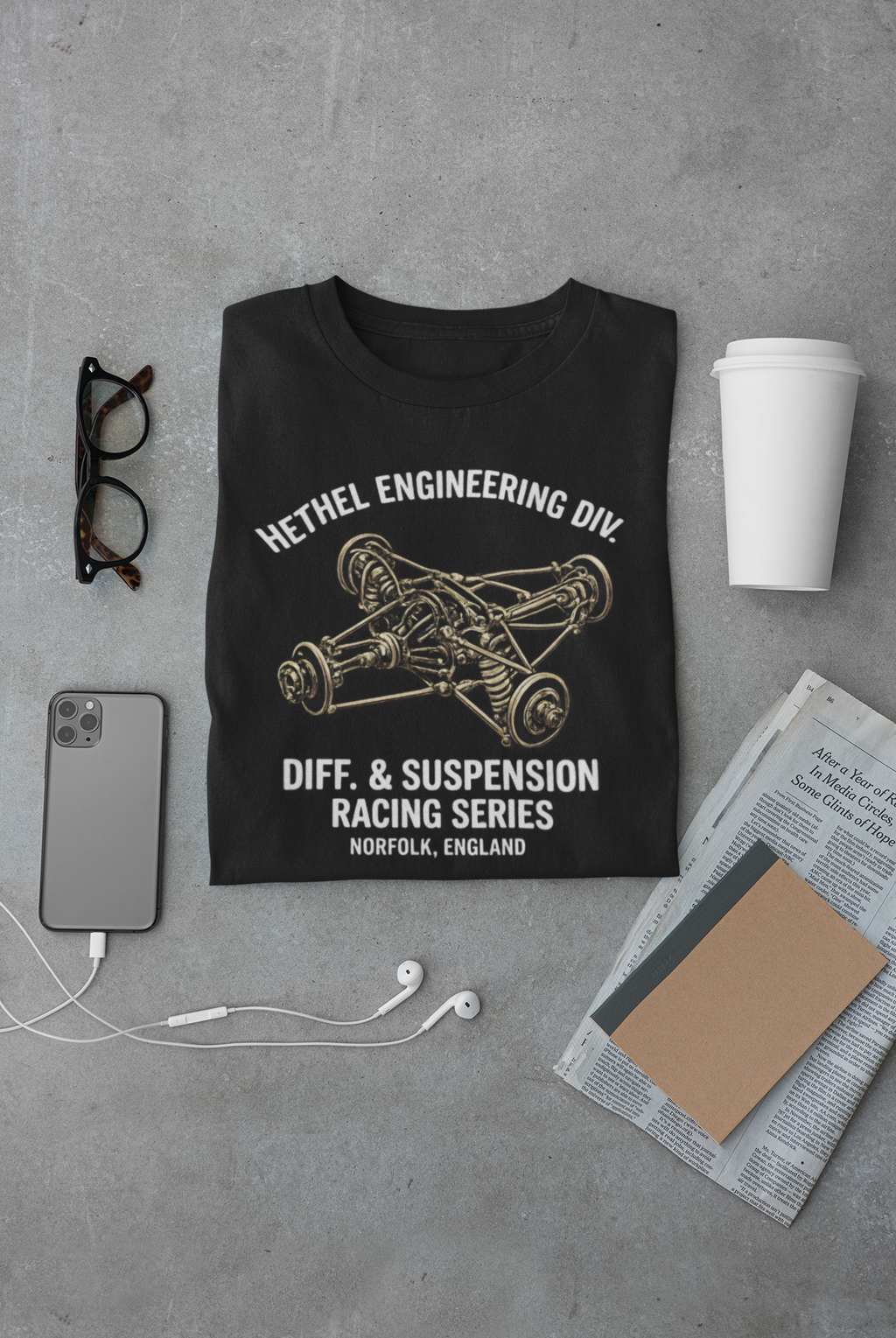 Black t-shirt with engineering graphic and text on a gray surface with accessories.