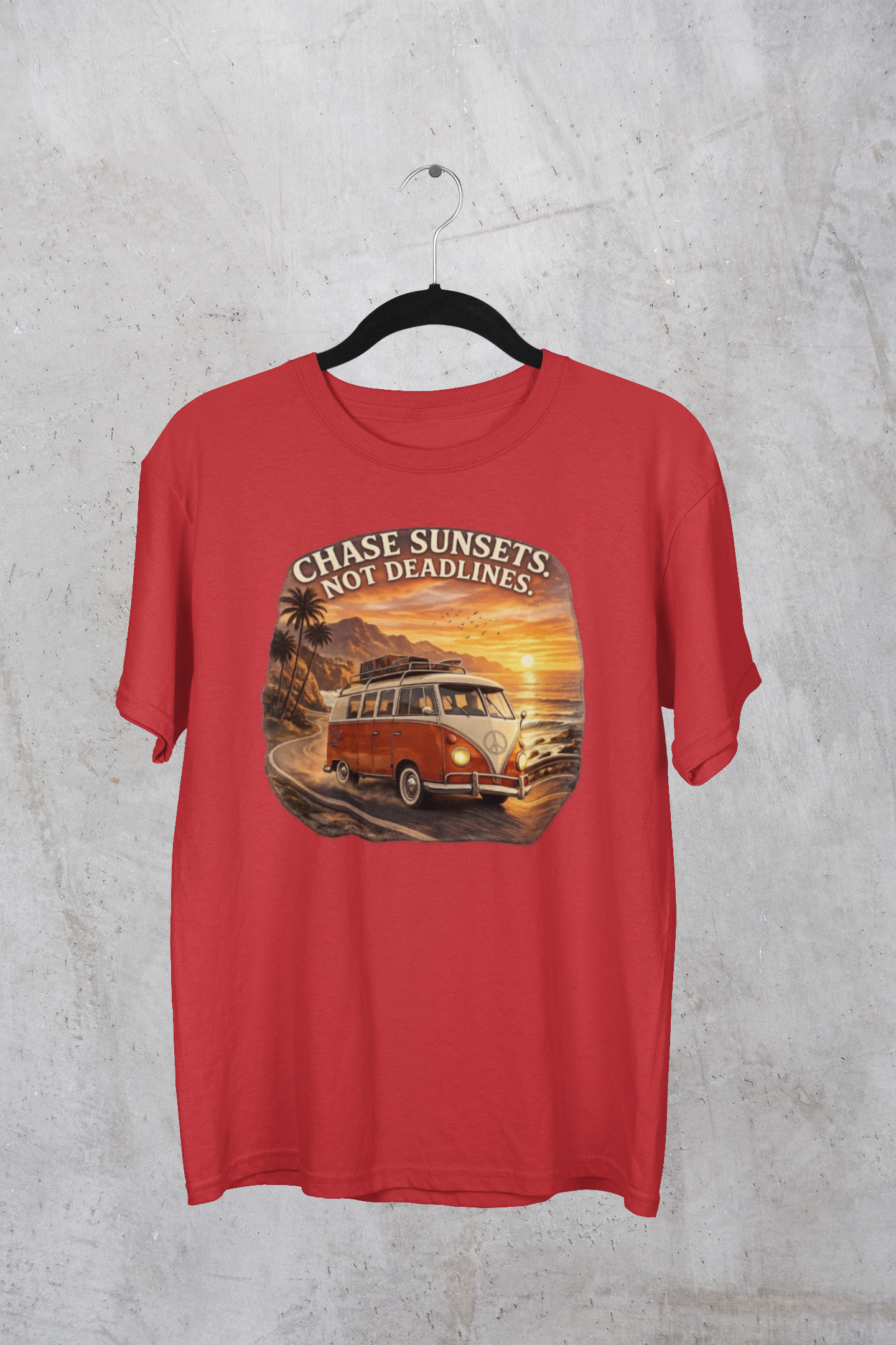 Red t-shirt with a graphic of a classic van and sunset text 'Chase sunsets not deadlines' on a textured gray background.
