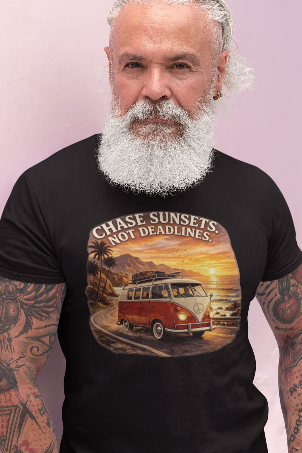 Man wearing a black t-shirt with a graphic red van design and text 'Chase Sunsets Not Deadlines' on a light pink background.