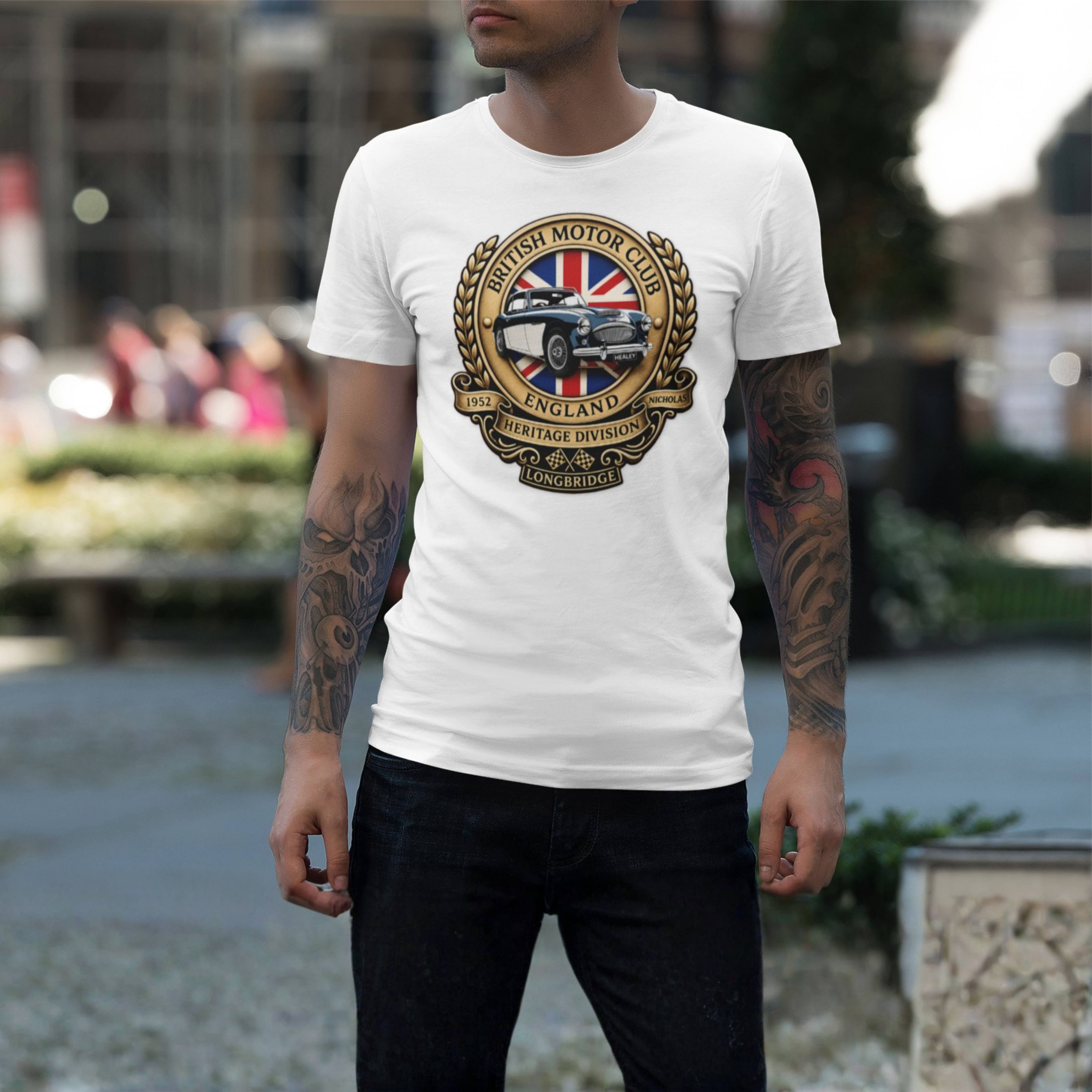 Man wearing a white t-shirt with a British Motor Club logo outdoors.