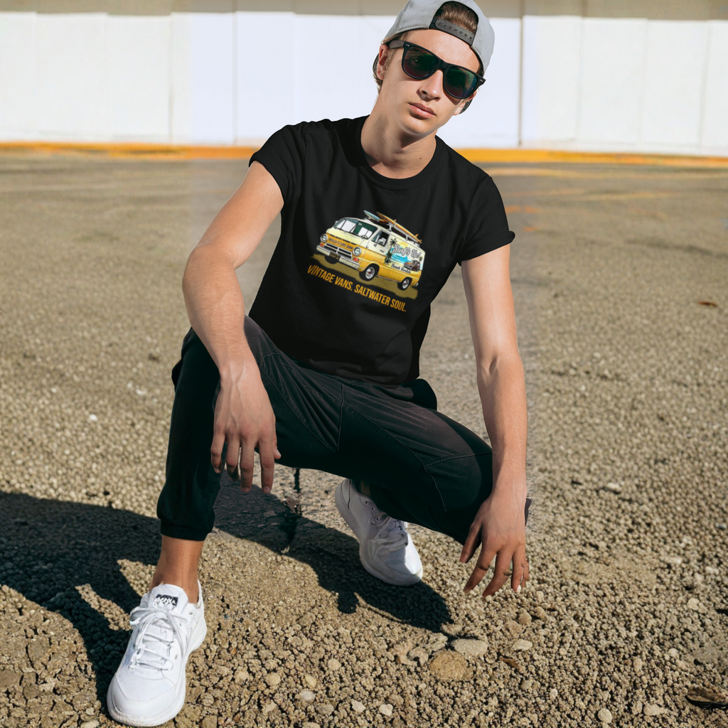 Man wearing a black t-shirt with a graphic classic van design, sunglasses, and a cap in an outdoor setting.