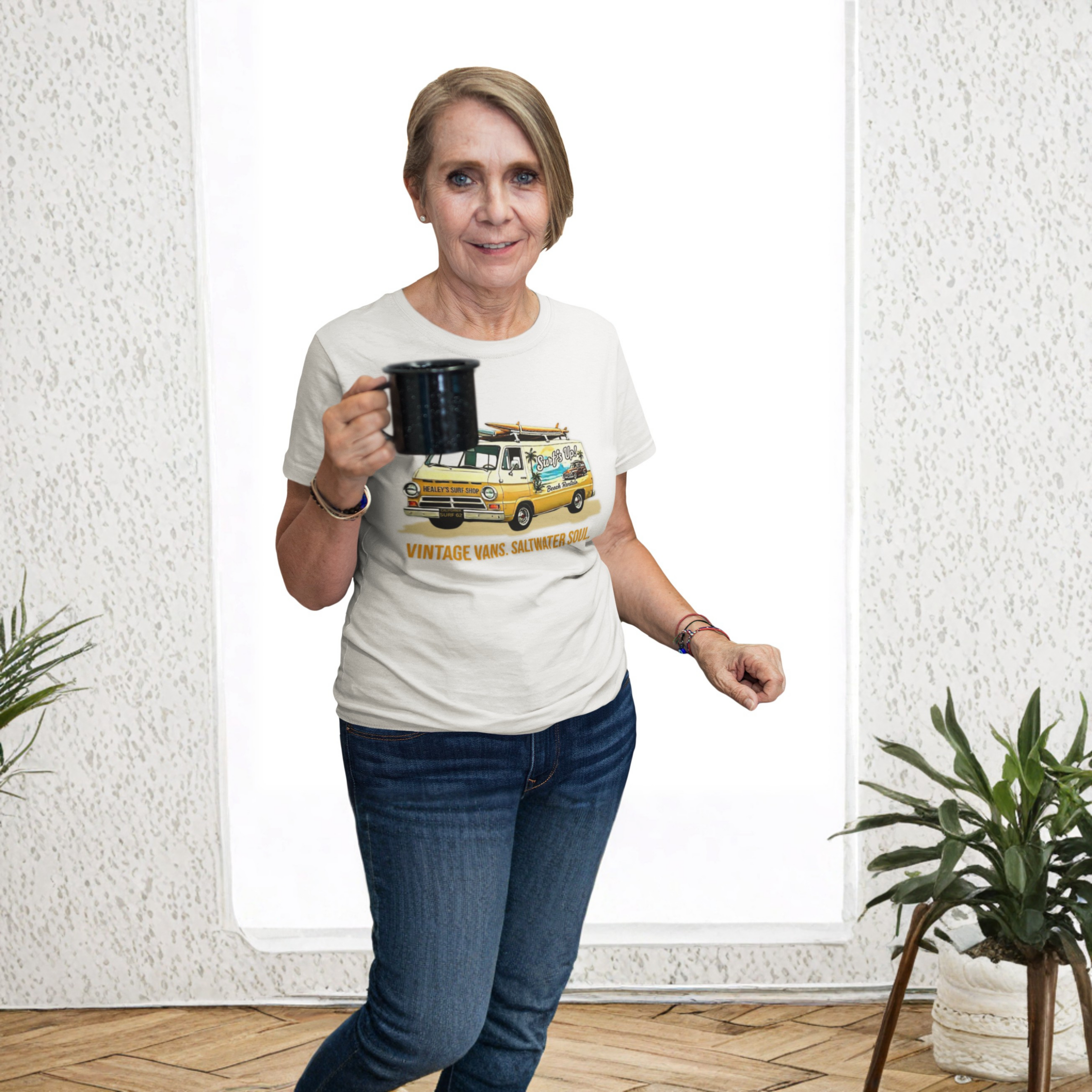 Woman wearing a white t-shirt with a vintage van design, holding a mug indoors.