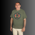 A man wearing an military green t-shirt with a circular 'Abingdon Motor Works' crest printed on the chest, paired with beige trousers, set against a dark gray gradient background.