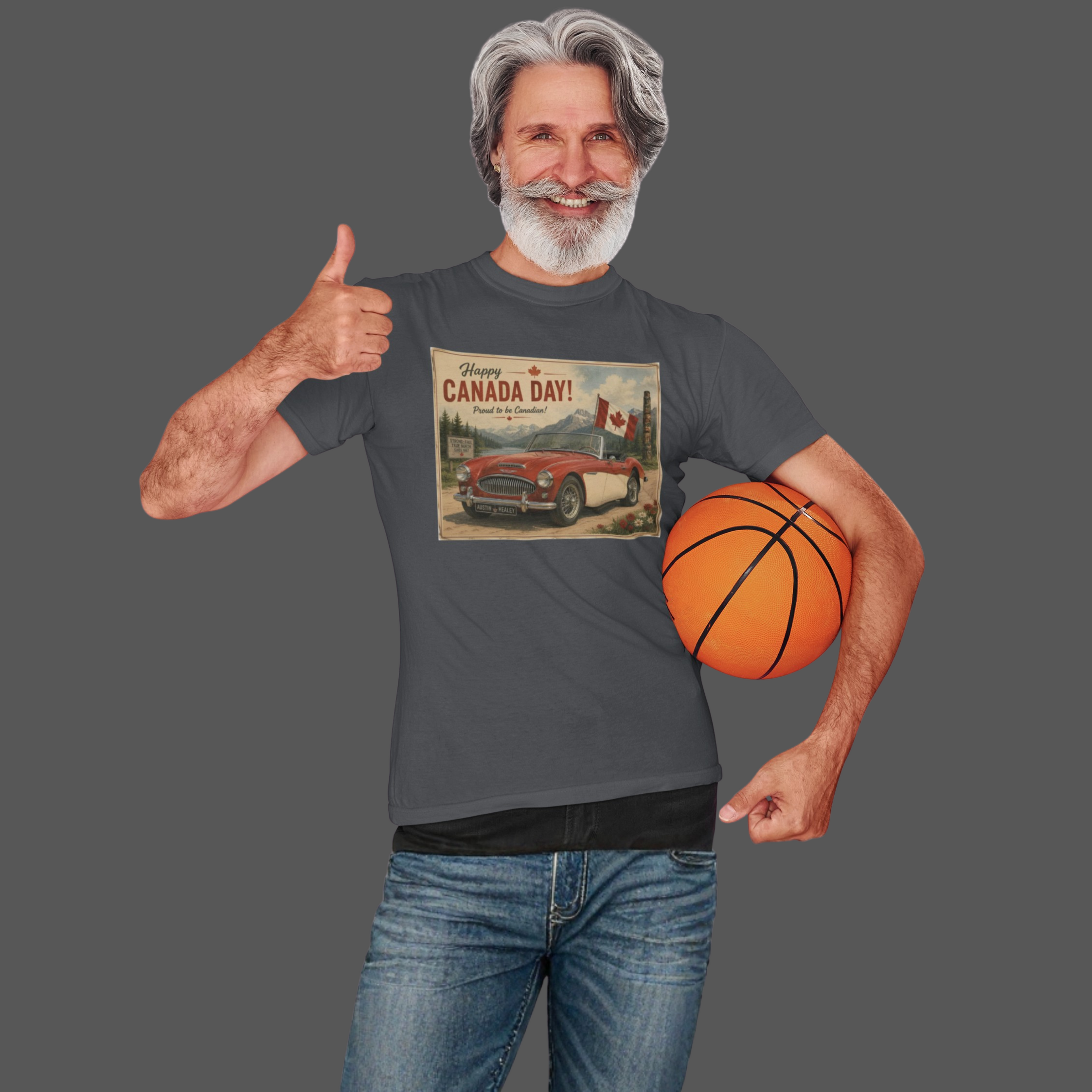 A man wearing a dark gray graphic t-shirt with a retro 'Happy Canada Day!' print, holding an orange basketball against a solid dark gray background.