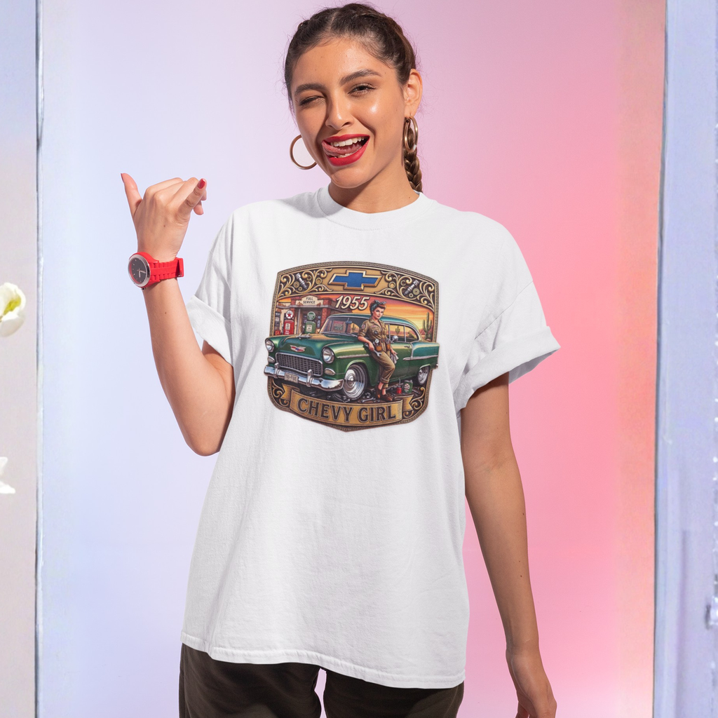 A woman modeling a white graphic t-shirt featuring a vintage-style illustration of a green 1957 Chevy with the text 'CHEVY GIRL' and '1957'. She is posing against a pastel pink and blue studio backdrop.