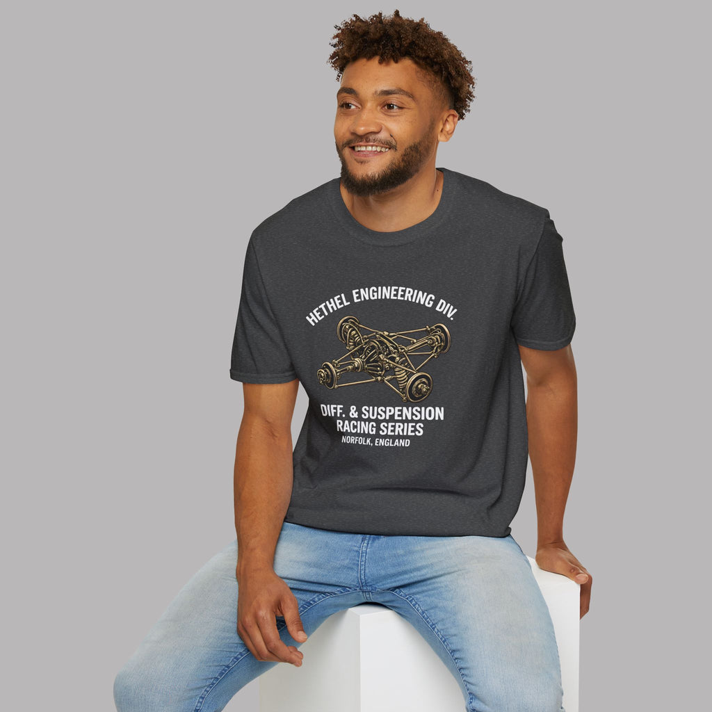 Man wearing a dark heather t-shirt with text and graphics, sitting on a white stool against a gray background.