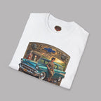 A folded white short-sleeve crewneck t-shirt featuring a vintage-style graphic print of a teal 1957 Chevrolet station wagon with a woman sitting on it, framed by a gold and brown border with the text 'CHEVY QUEEN', on a gray background.