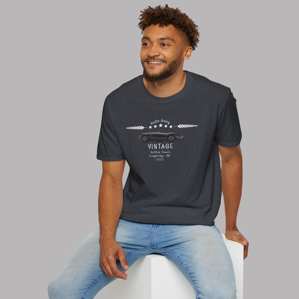 Man wearing a dark heather t-shirt with vintage design sitting on a white stool against a gray background