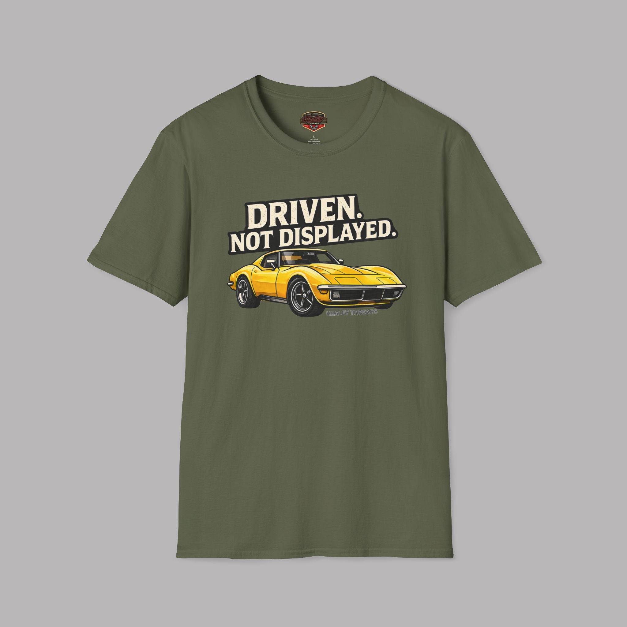 Military green t-shirt with a yellow muscle car graphic and text 'Driven. Not Displayed.' on a gray background