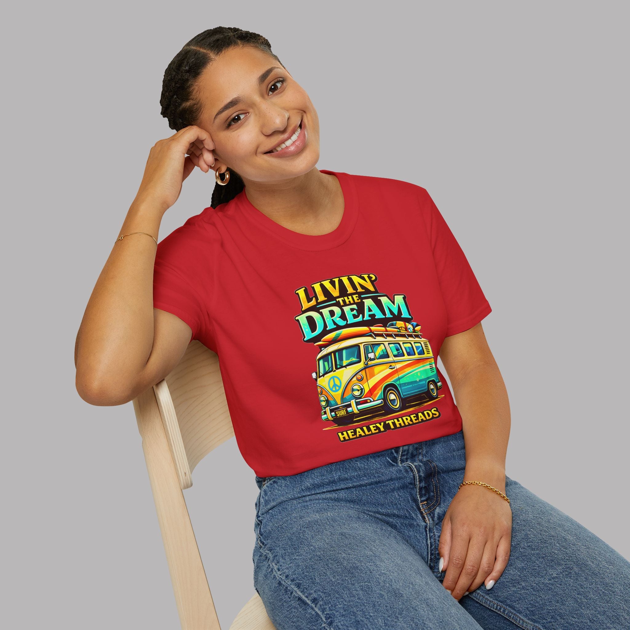 Woman wearing a red t-shirt with a colorful van graphic and text, sitting on a chair against a gray background.