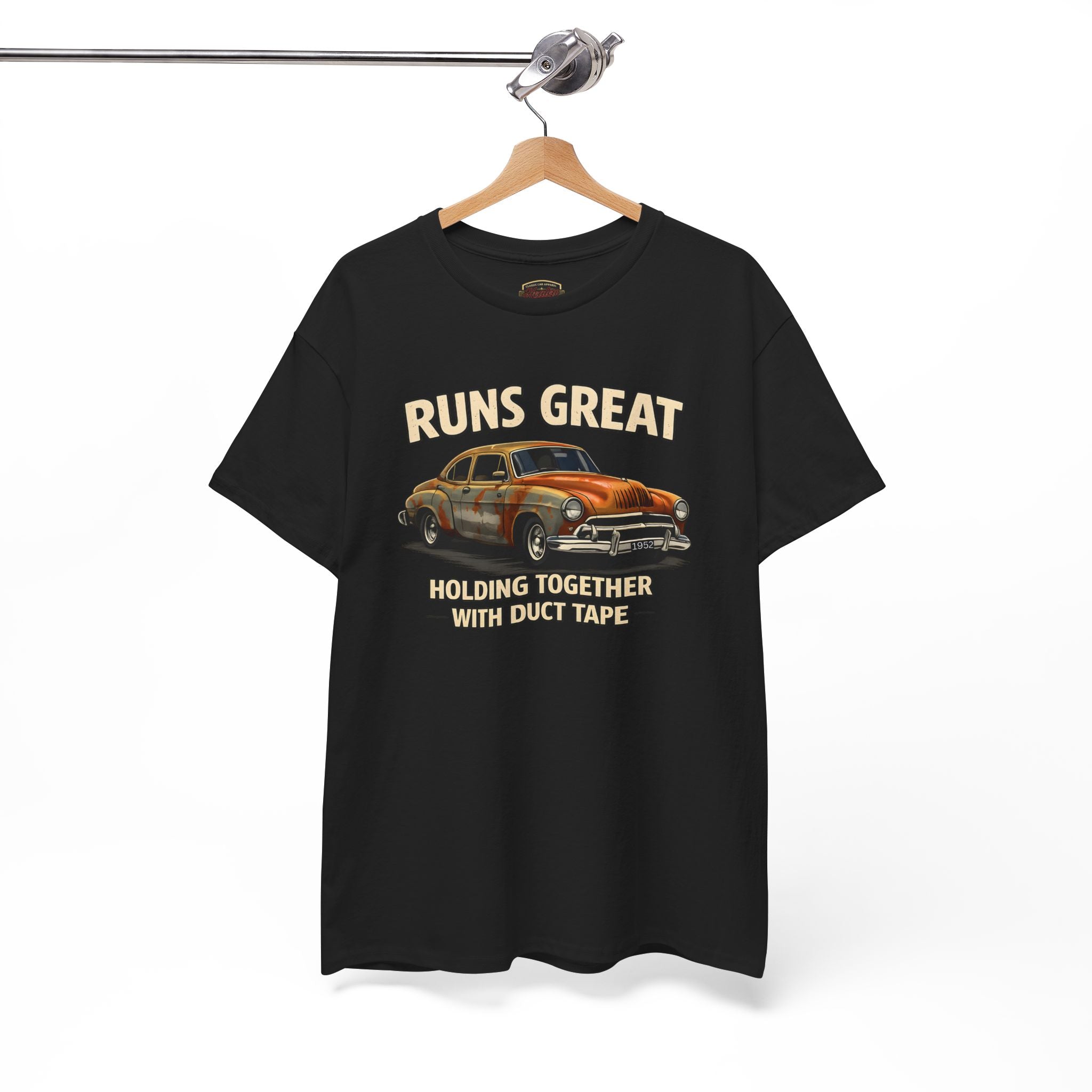 Black t-shirt with a graphic of an old car and text 'RUNS GREAT HOLDING TOGETHER WITH DUCT TAPE' on a hanger against a white background.