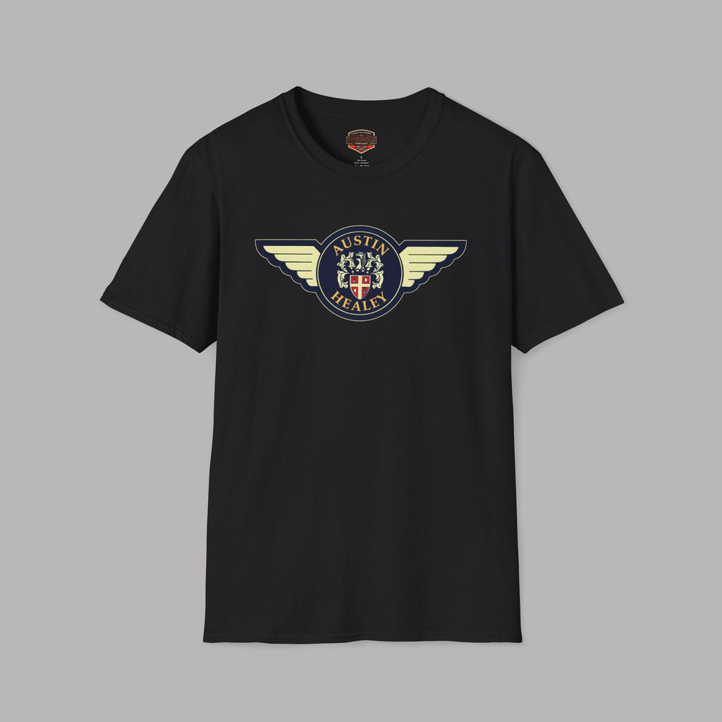 Austin Healey winged badge logo with navy and gold circular emblem, heraldic shield, and cream wings on a black t-shirt flat on gray background