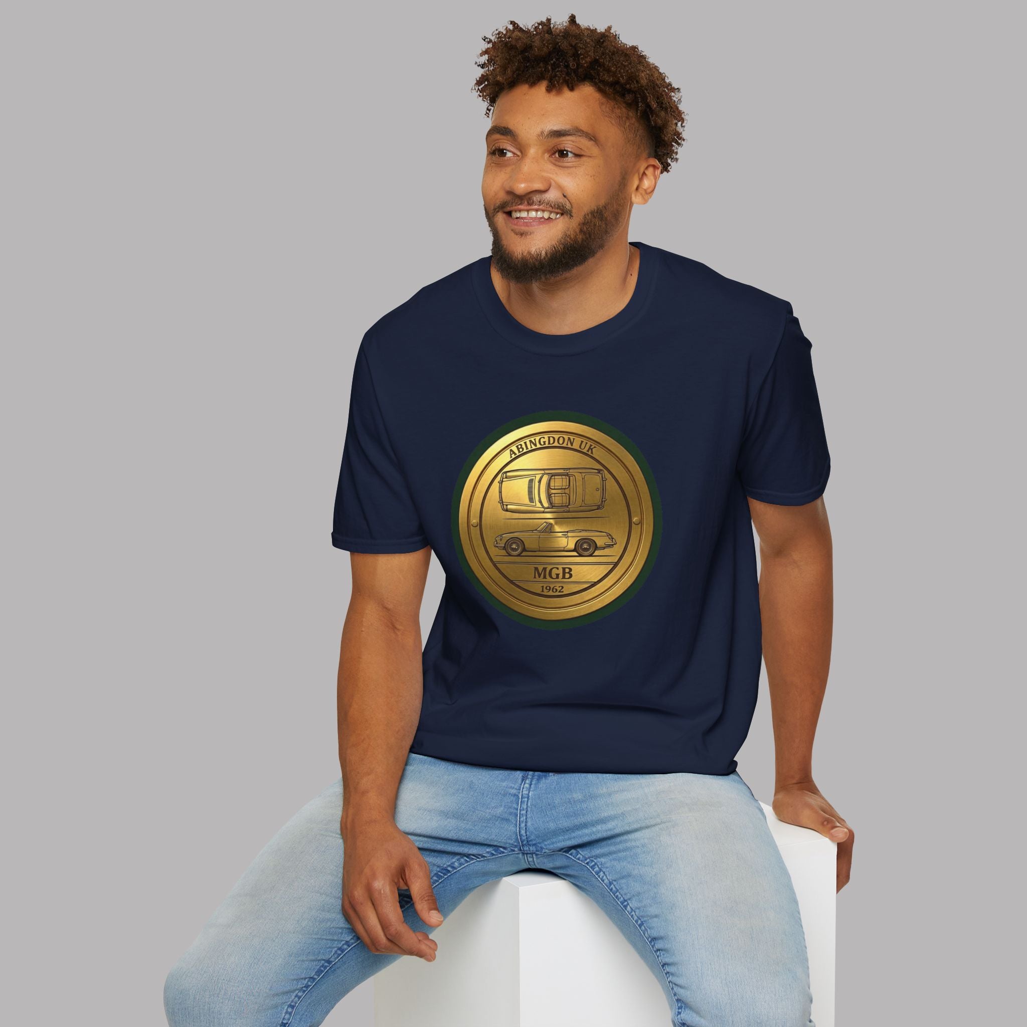 Man wearing a navy blue t-shirt with a gold classic car emblem on a gray background