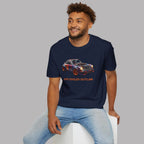 Man wearing a navy blue t-shirt with a car graphic and text, sitting on a white stool against a gray background.