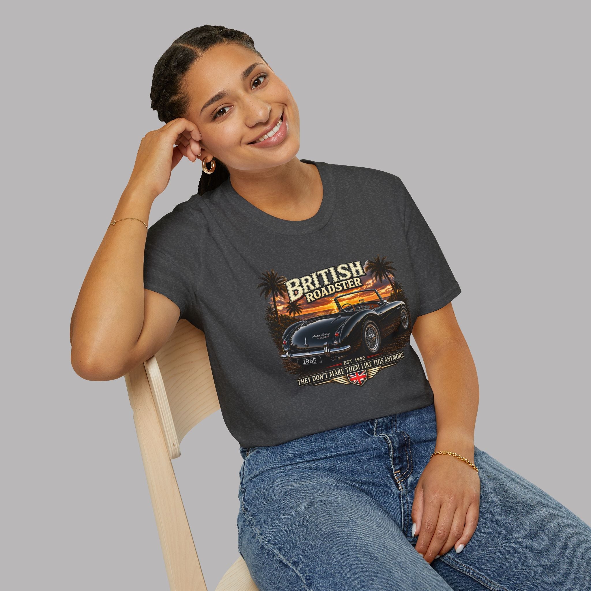 Woman wearing a dark gray t-shirt with a graphic design of a vintage car and 'British Roadster' text, sitting on a chair against a plain background.