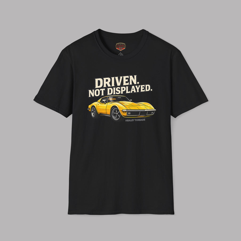 Black t-shirt with yellow muscle car graphic and text 'Driven. Not Displayed.' on a gray background
