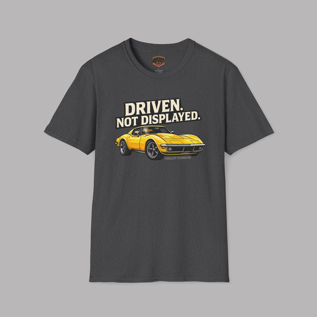 Dark heather t-shirt with a yellow muscle car graphic and text 'Driven. Not Displayed.' on a gray background