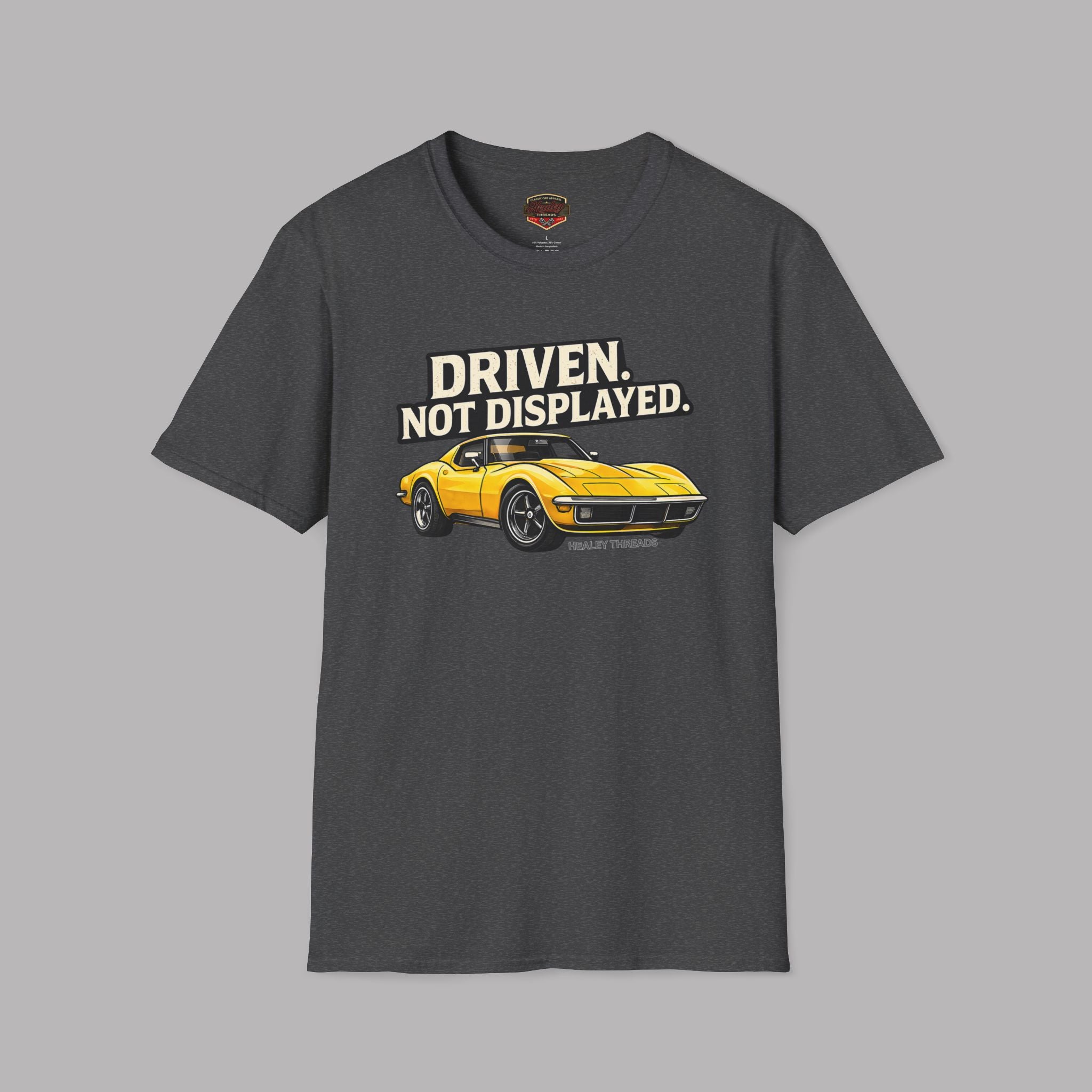 Dark heather t-shirt with a yellow muscle car graphic and text 'Driven. Not Displayed.' on a gray background
