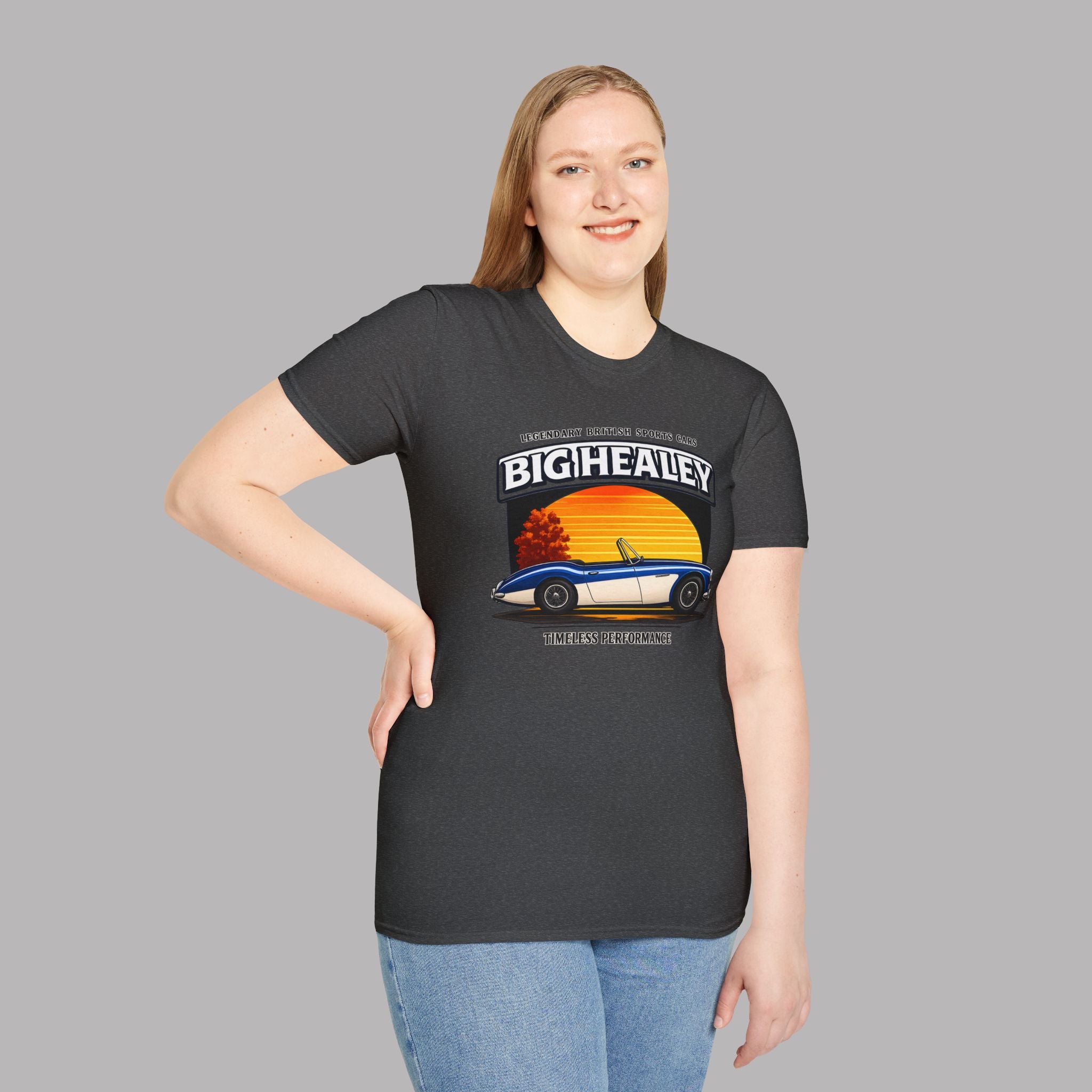 Woman wearing a Big Healey graphic dark heather colored t-shirt featuring a blue and white Austin Healey roadster with retro sunset artwork and vintage British sports car on a gray background 