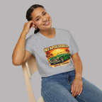 Woman wearing a gray t-shirt with a graphic design of a green classic car and 'No Apologies' text, sitting on a chair against a plain background.