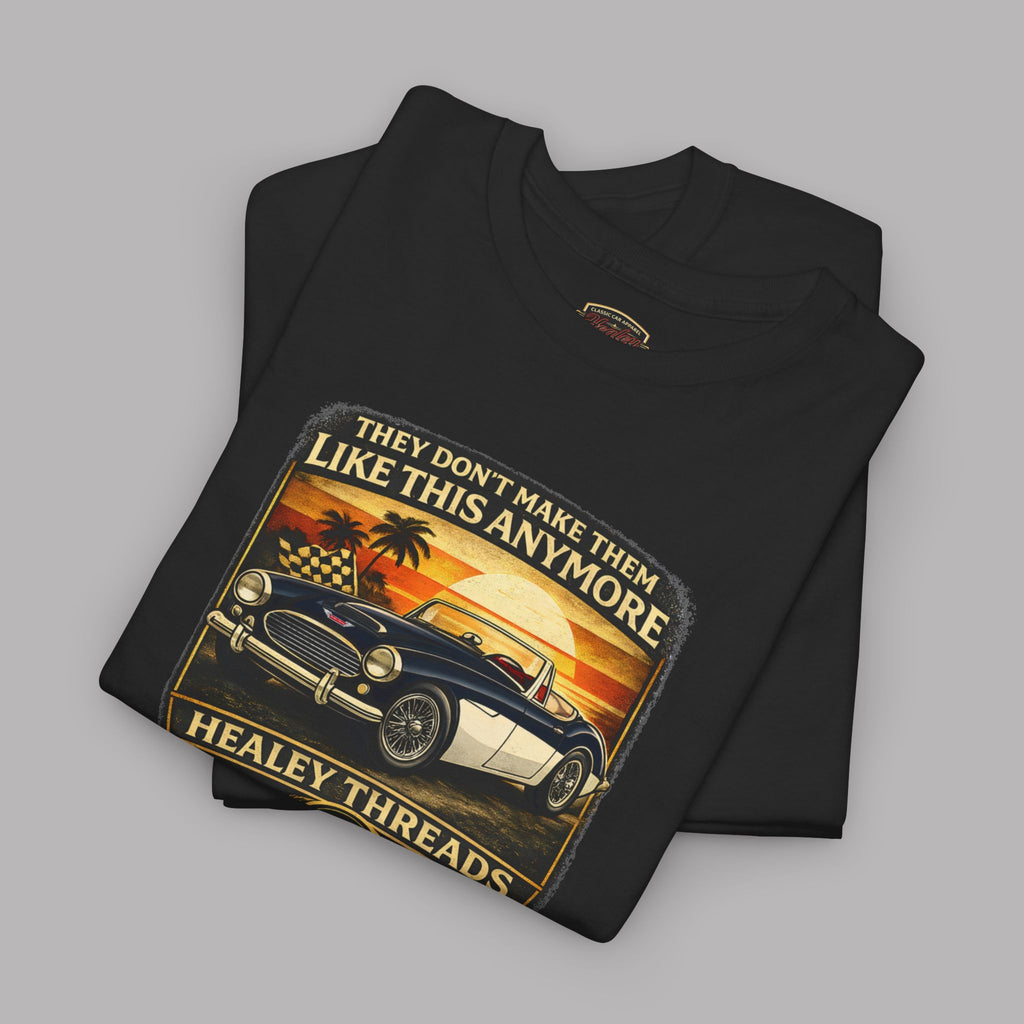 Folded black t-shirt with vintage car graphic and 'Healey Threads' branding on a gray background